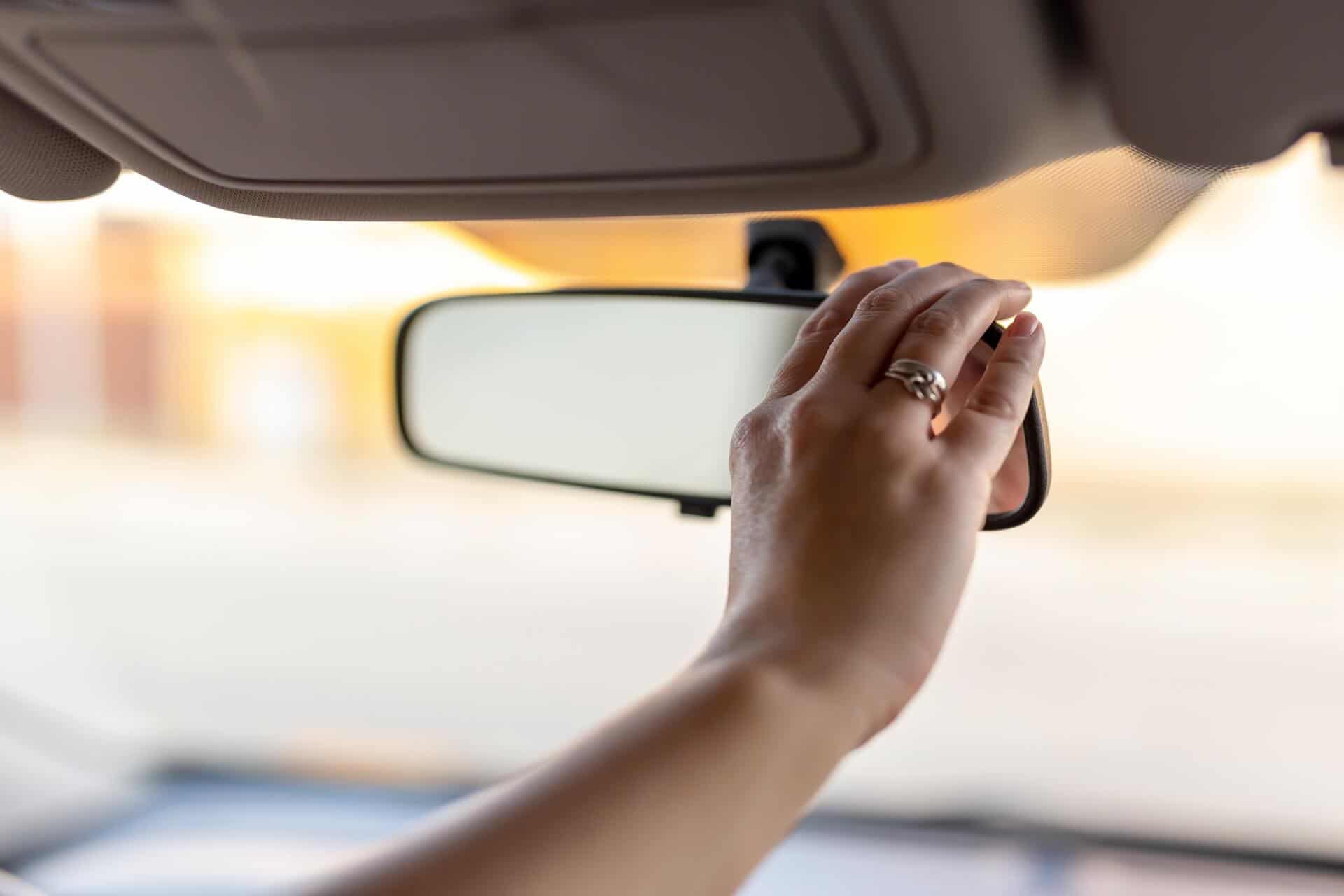Woman adjusting view in rearview mirror